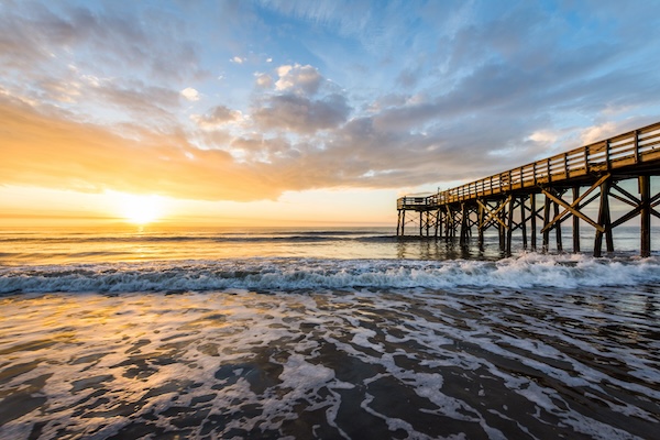 Pier on the ocean with waves rolling in