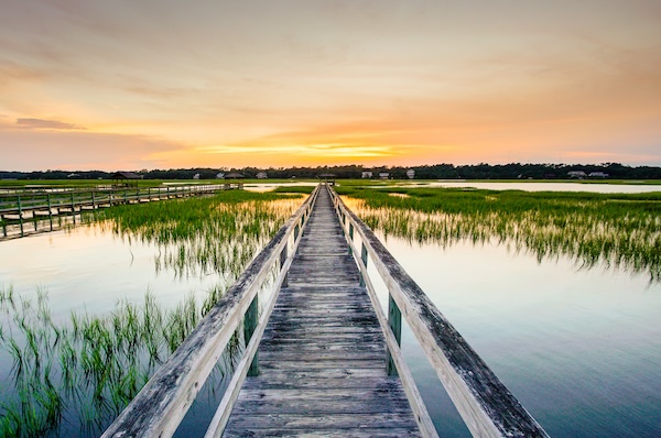 Long wooden walkway to boat dock on the water
